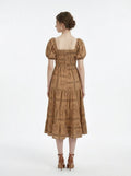 Back view of a woman in a tan midi dress with a smocked bodice and puff sleeves, showcasing the all-over print.