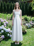 Woman wearing a white satin floor-length dress with a square neckline and tank straps, standing in a garden with hydrangeas.