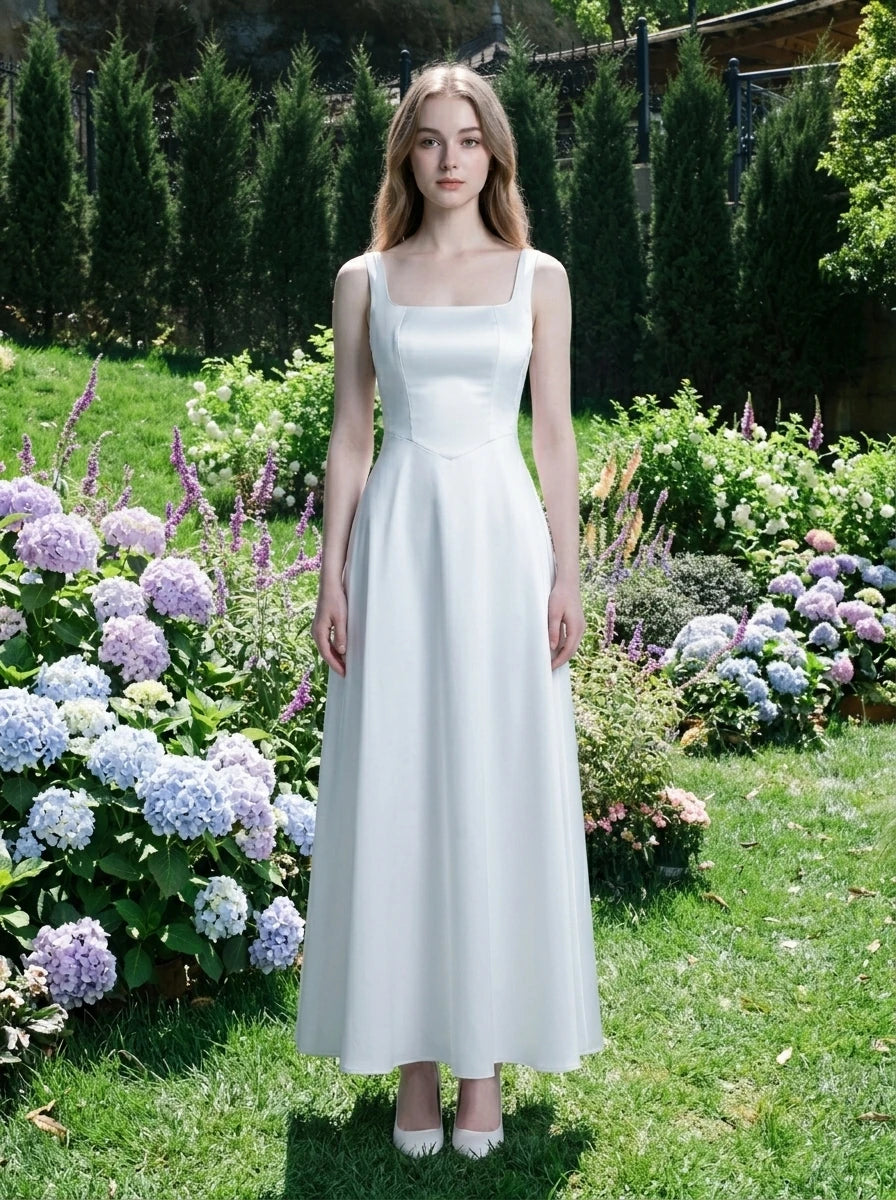 Woman wearing a white satin floor-length dress with a square neckline and tank straps, standing in a garden with hydrangeas.