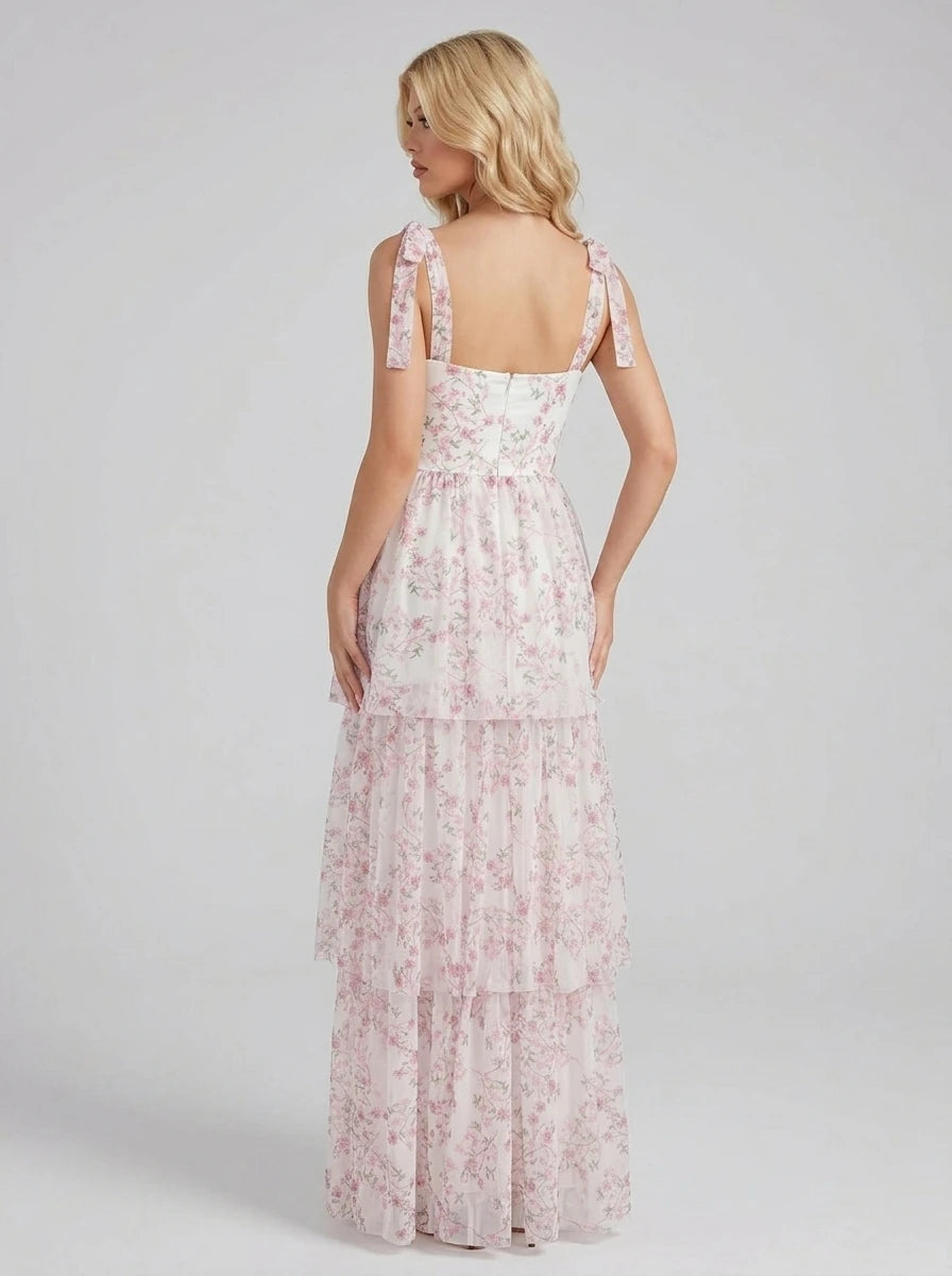 Back view of a woman in a white and pink floral print tiered maxi dress