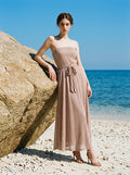 Woman wearing a strapless metallic knit A-line maxi dress with a self-tie belt on a beach