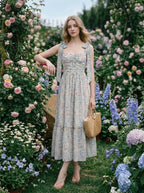 Woman in a floral print midi dress posing in a garden with flowers