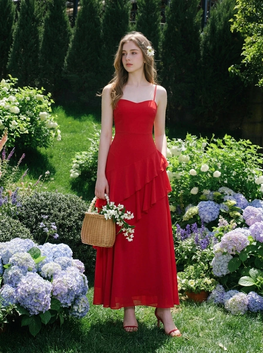 Woman in a red, floor-length, spaghetti strap dress with ruffle detailing, holding a wicker basket of flowers in a garden