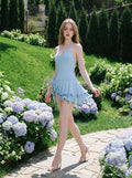 Woman walking in a light blue ruffled halter dress on a garden path