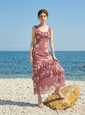 Woman on a beach wearing a floral print chiffon maxi dress with ruffled neckline