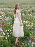 Woman standing in a field of wildflowers wearing a floral print midi dress.