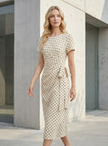 Woman walking outdoors wearing a cream polka dot midi wrap dress