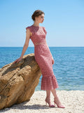 Model leaning on a rock in Dusty Rose Lace Midi Dress by the sea