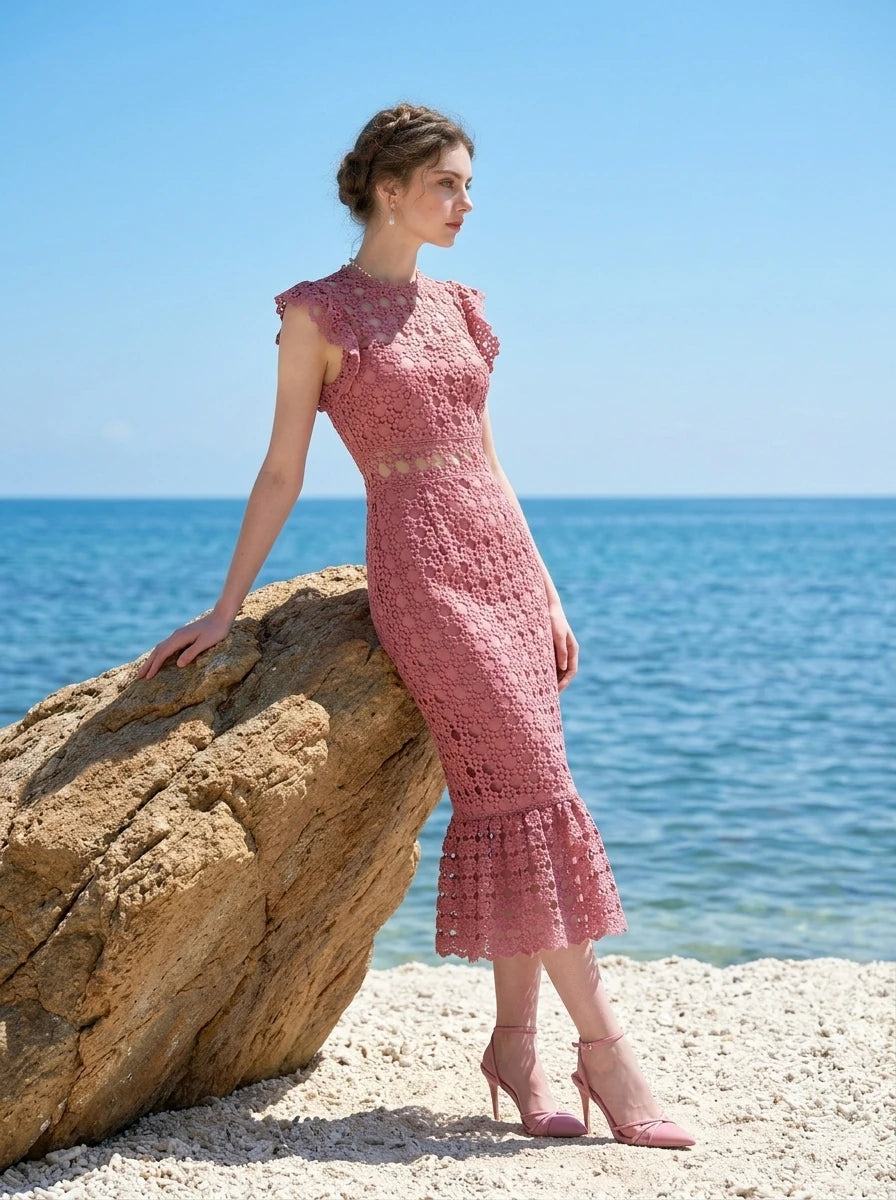 Model leaning on a rock in Dusty Rose Lace Midi Dress by the sea