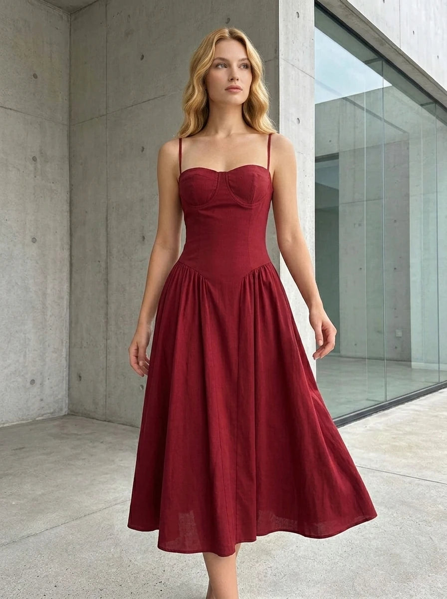 Woman standing outdoors wearing a deep red linen blend midi dress with a sweetheart neckline and full skirt