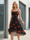 Woman walking in a black midi dress with a red poppy print and a high-low hem