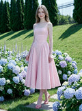 woman in a pink gingham dress posing in a garden with hydrangeas