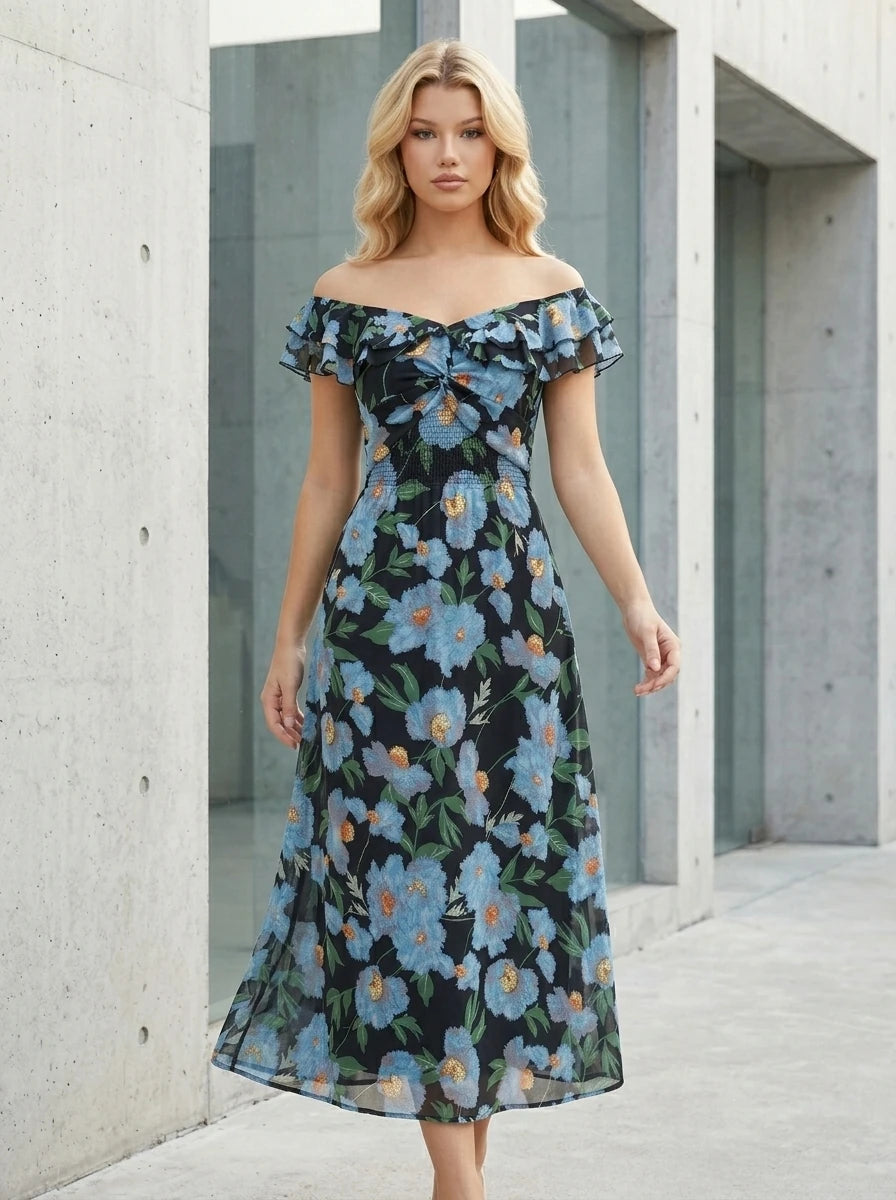 Woman standing outdoors wearing a black floral print off-the-shoulder midi dress with blue flowers