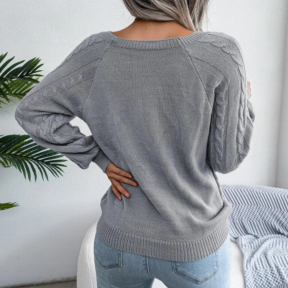 Back view of a woman wearing a grey cable knit sweater, showcasing the raglan sleeves and knit pattern
