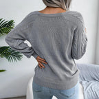 Back view of a woman wearing a grey cable knit sweater, showcasing the raglan sleeves and knit pattern