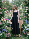 woman in a black midi halter dress surrounded by flowers