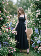 woman in a black midi halter dress surrounded by flowers