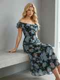 Woman sitting on a bench wearing a black floral print off-the-shoulder midi dress with blue flowers