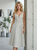 Woman standing next to a pillar in a white polka dot sleeveless dress