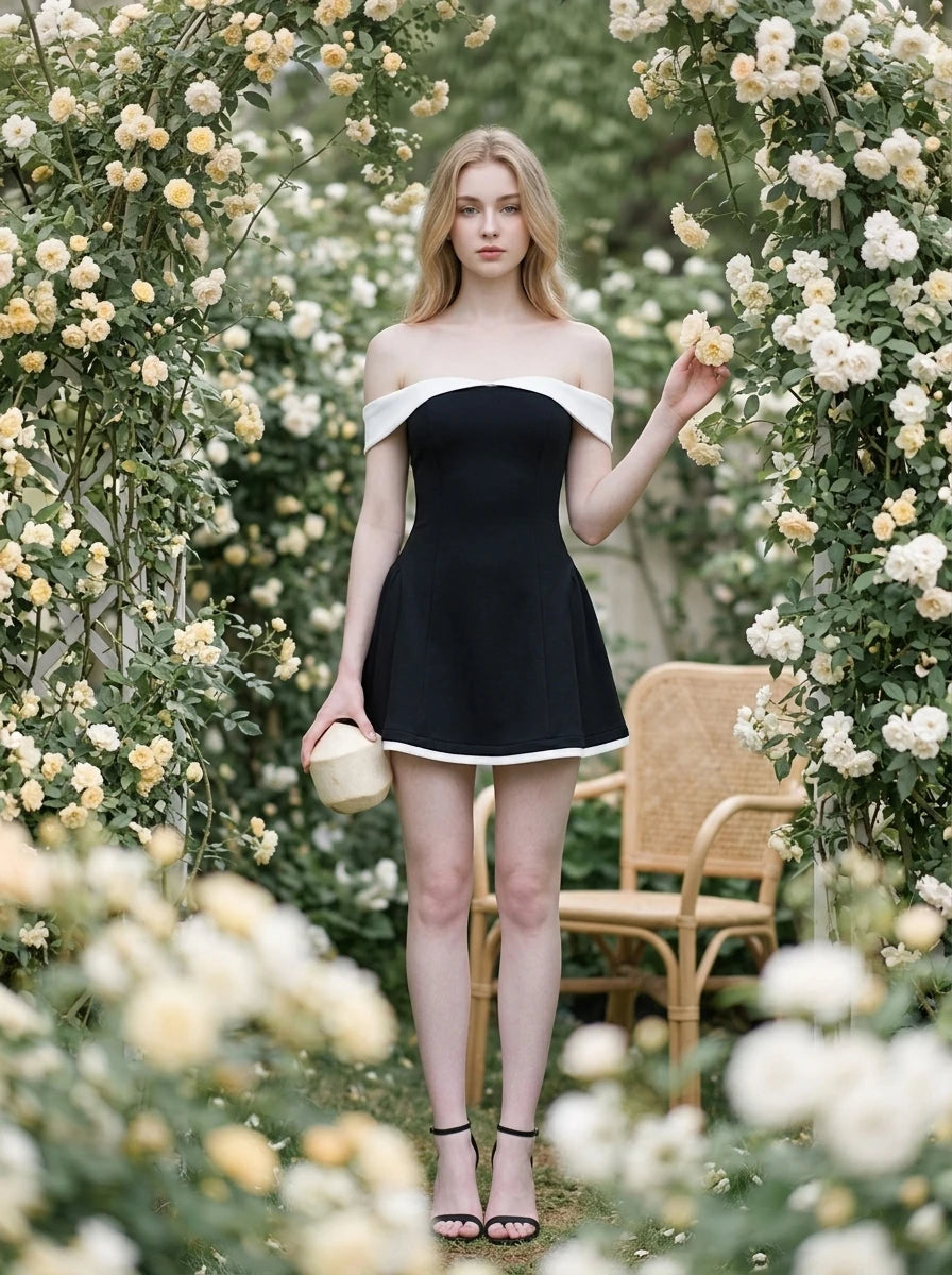 Woman in a black off-the-shoulder dress with white trim standing among flowers