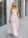 Woman walking outdoors wearing a white and pink floral print tiered maxi dress and carrying a clutch
