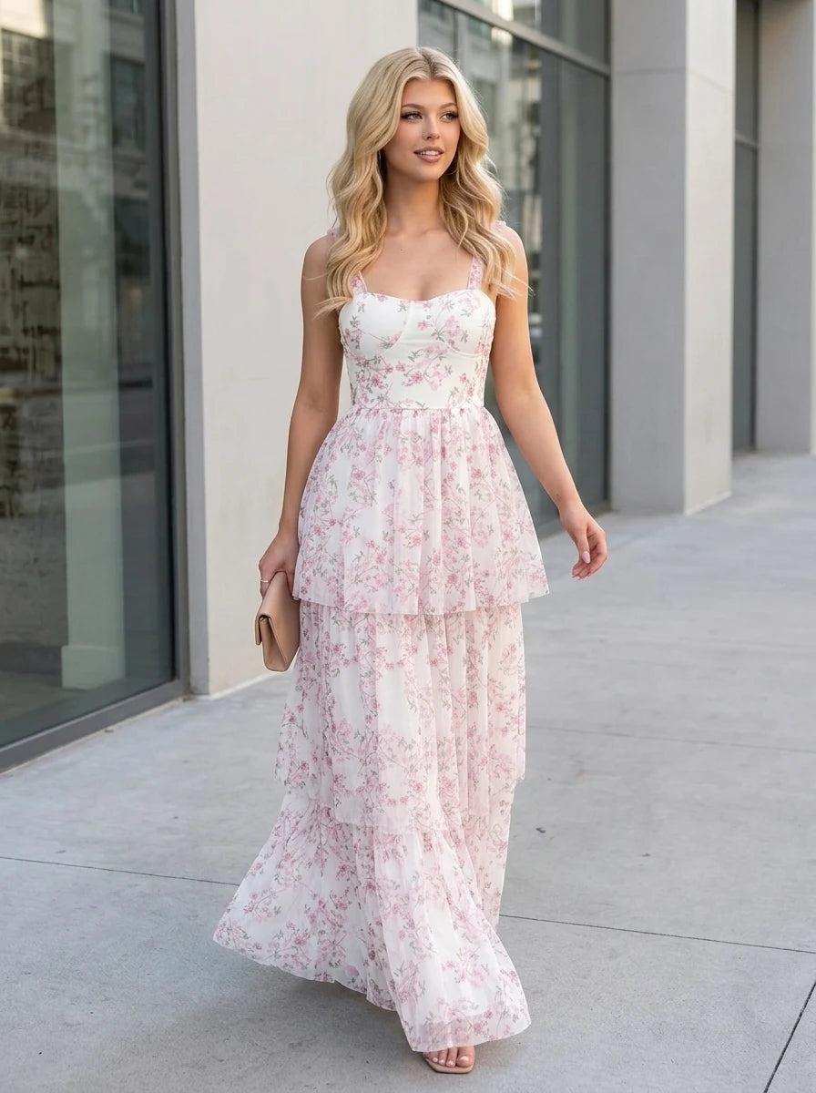 Woman walking outdoors wearing a white and pink floral print tiered maxi dress and carrying a clutch