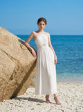 Woman wearing a white halter neck midi dress on a sandy beach