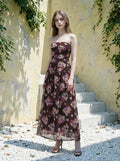 Woman in a strapless floral print chiffon maxi dress standing on steps