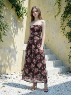 Woman in a strapless floral print chiffon maxi dress standing on steps