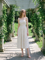 Woman posing under a pergola wearing a floral print midi dress.