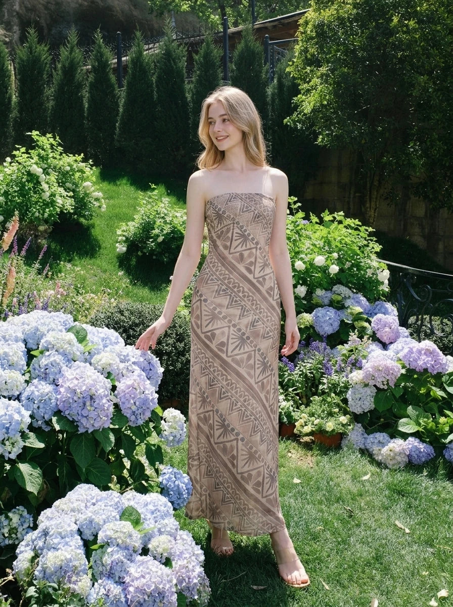 Woman posing in a garden wearing a strapless geometric print maxi dress