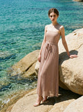 Woman wearing a strapless metallic knit A-line maxi dress with a self-tie belt standing by the ocean