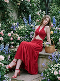 Woman sitting in a garden wearing a red halter neck crop top and tiered maxi skirt.