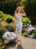 Woman wearing a floral print midi dress standing in a garden with hydrangeas.