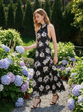 Woman in a garden wearing a black floral print halter maxi dress