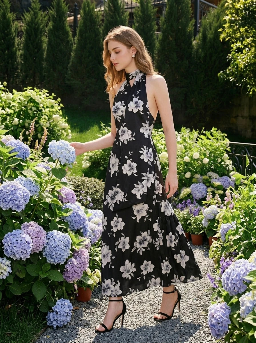Woman in a garden wearing a black floral print halter maxi dress
