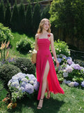 Woman in a bright pink ruched maxi dress with spaghetti straps and butterfly details, walking through a garden with hydrangeas.