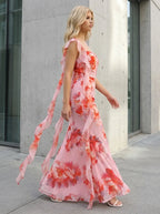 Woman walking outdoors in a pink floral print chiffon maxi dress with ruffle trim