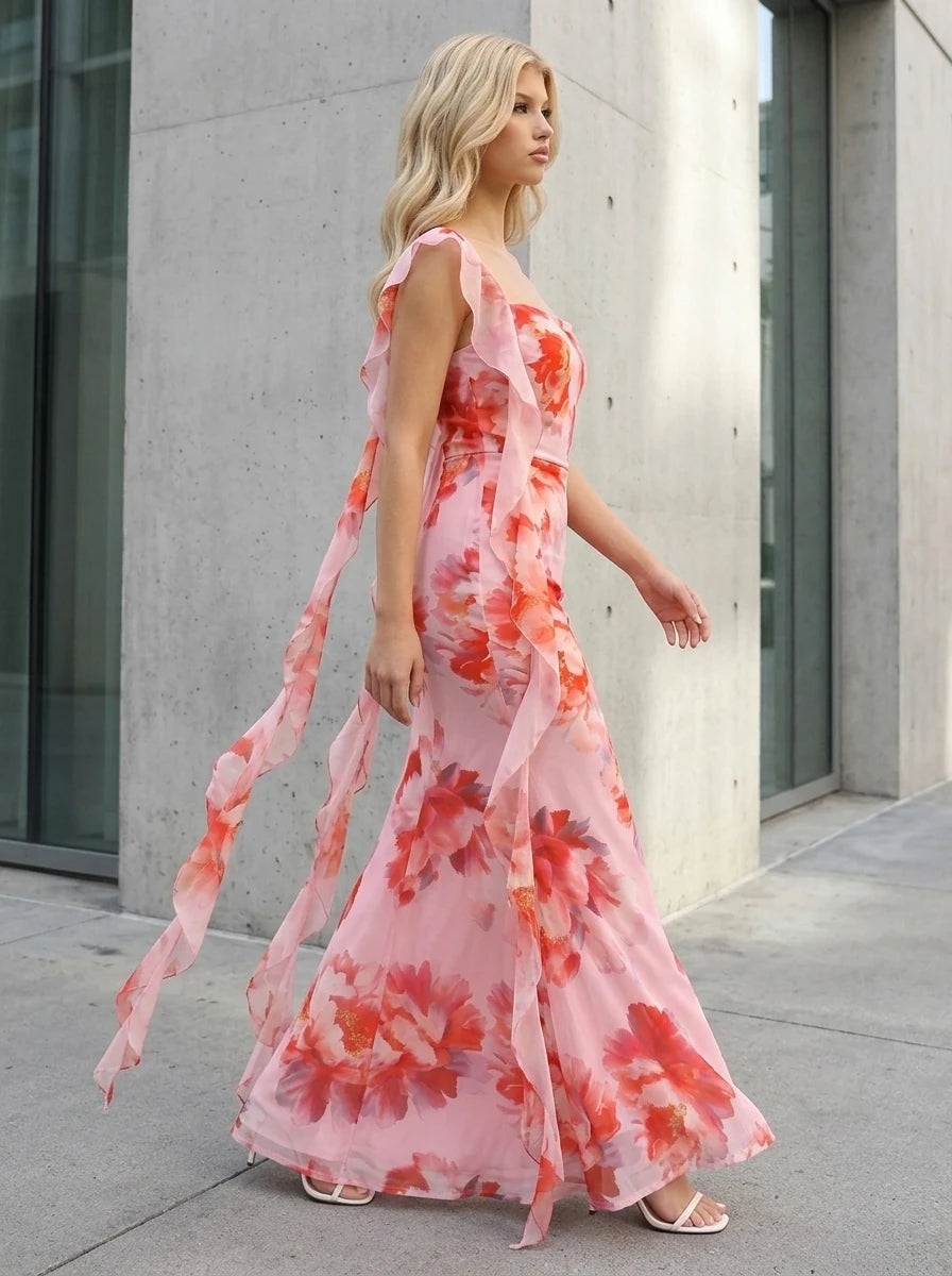 Woman walking outdoors in a pink floral print chiffon maxi dress with ruffle trim