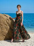 Woman in a dark green floral print maxi dress posing on a sandy beach
