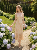 Woman wearing a cream-colored midi dress with 3D floral embellishments and a ruffled hem, walking in a garden with hydrangeas.