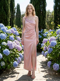 Woman in a dusty rose satin one-shoulder maxi dress with a high slit, posing outdoors in a garden with hydrangeas.