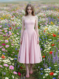 woman in a pink gingham dress walking through a field of wildflowers