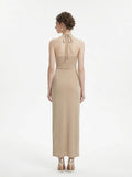 Back view of a champagne sparkly knit halter neck maxi dress with a cutout waist and thigh-high slit
