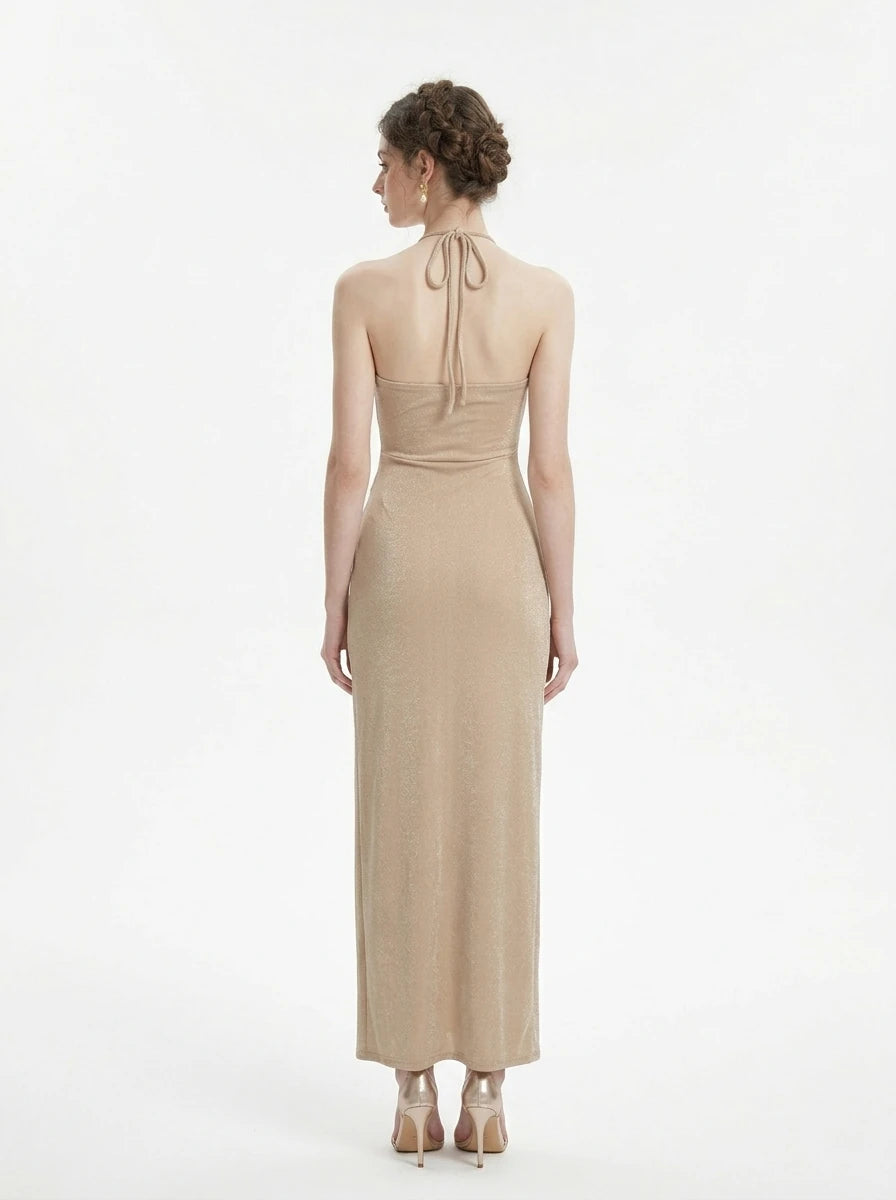 Back view of a champagne sparkly knit halter neck maxi dress with a cutout waist and thigh-high slit