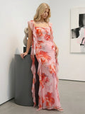 Woman standing next to a pedestal in a pink floral print chiffon maxi dress with ruffle trim