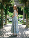 Woman posing in a garden wearing a light blue floral print midi dress