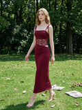 Woman walking in a park wearing a burgundy midi dress with lace accents.