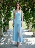 Woman wearing a sky blue strapless ruched jersey knit A-line evening dress with an asymmetrical hemline and side slit in a garden setting