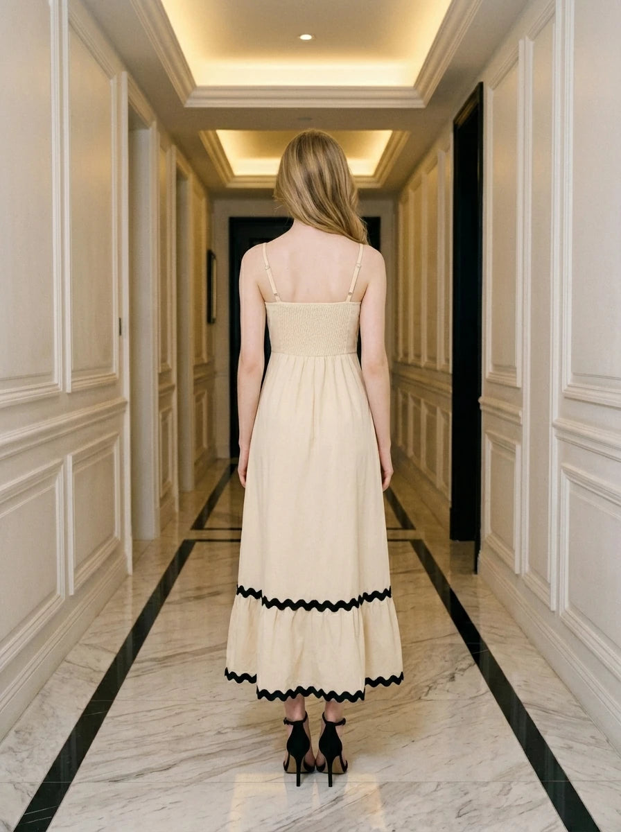 Rear view of a woman in a cream-colored midi dress with black trim and a smocked back.